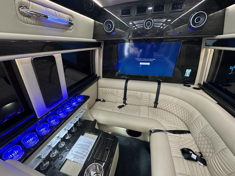 The van's lounge seating with a lit bar and television